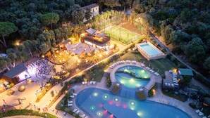 An aerial view of a resort with a swimming pool, outdoor seating areas, and a tennis court. - Mobilhome im Ferienpark mit Grosser Poolanlage (Castiglione della Pescaia)