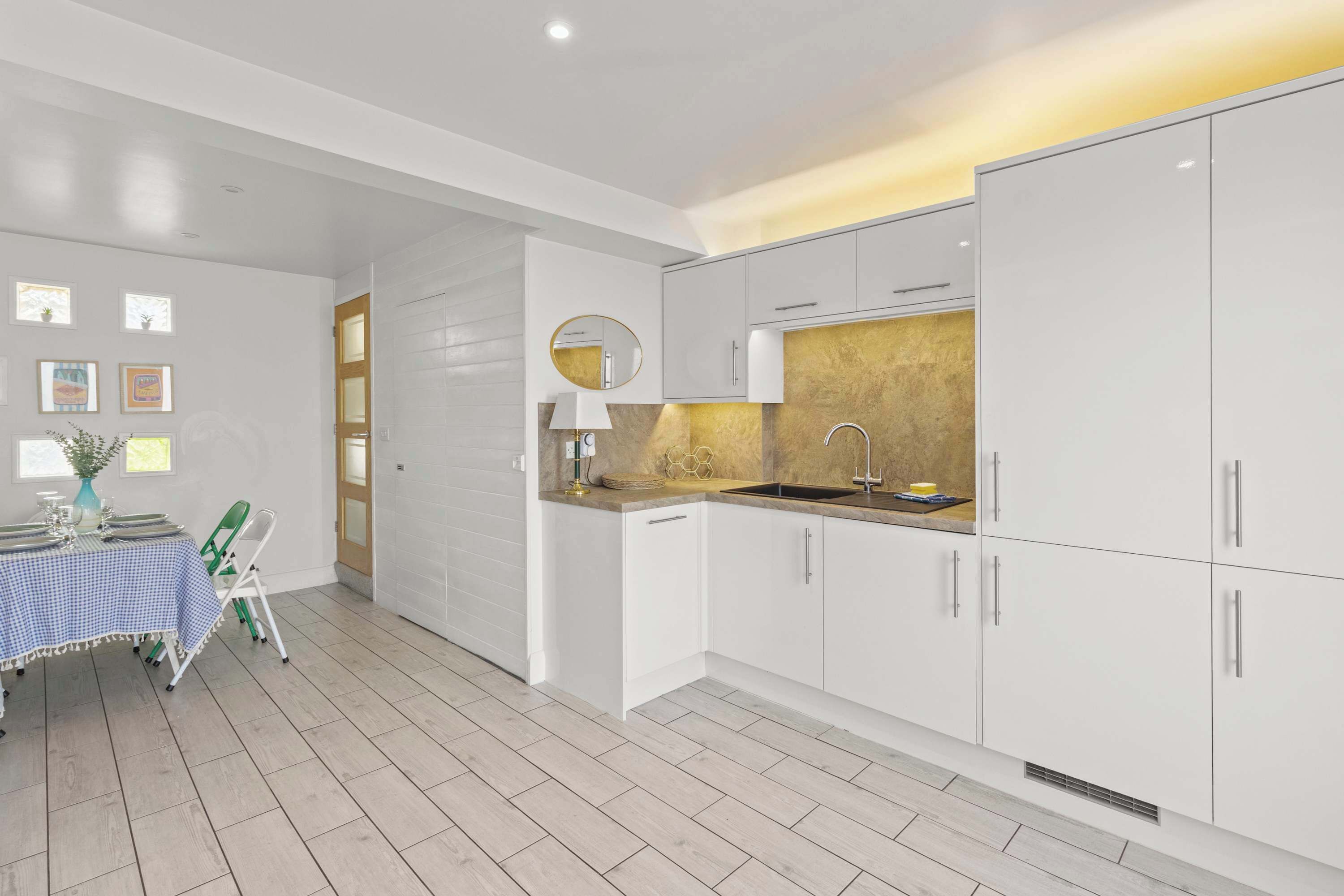 A modern kitchen with white cabinets, a sink, and a dining area with a table and chairs.
