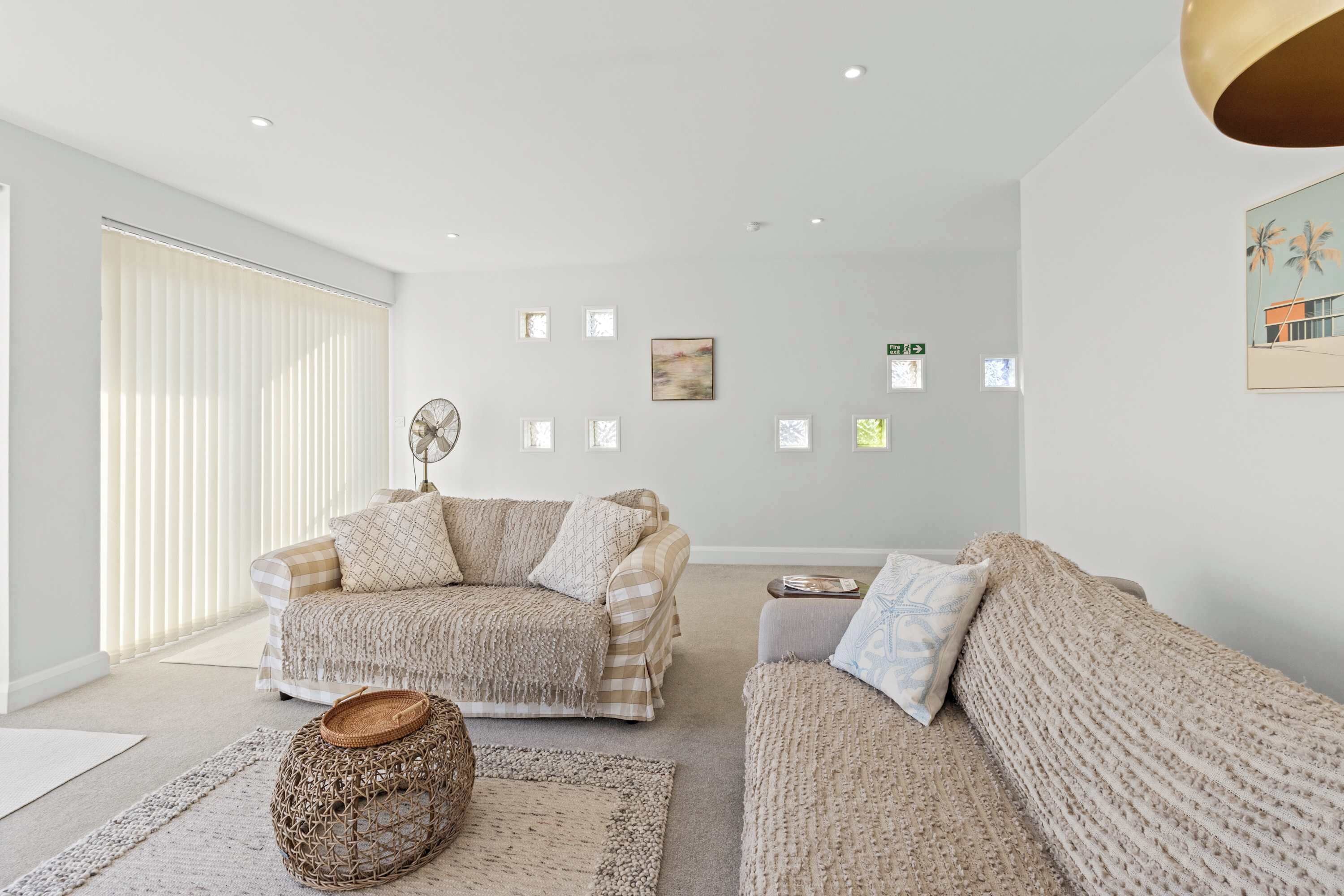 A modern living room with a sofa set, a coffee table, and a woven ottoman.