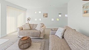 A modern living room with a sofa set, a coffee table, and a woven ottoman. - Beachside Coastal Retreat with Ocean Views (Pevensey Bay)