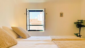 Een slaapkamer met twee bedden, een raam en een kamerplant.