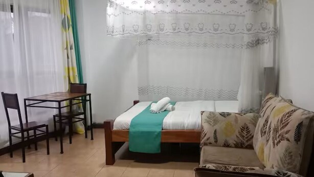 Una habitación con una cama, un sofá, una mesa de comedor con sillas y una mesita con una silla.