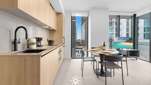A modern kitchen with a sink, stove, and dining area with chairs and a table. - City Views with Bright 1BR Refined in 501 Miami (Miami)