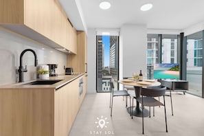 A modern kitchen with a sink, stove, and dining area with chairs and a table. - City Views with Bright 1BR Refined in 501 Miami (Miami)