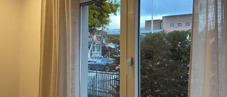 A room with a large window, a door, and a view of the street outside.