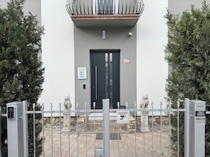 A building entrance with a black door, a security camera, and a sign indicating a room/camera location. - OTB ITALIA - Airport Rooms (Treviso)