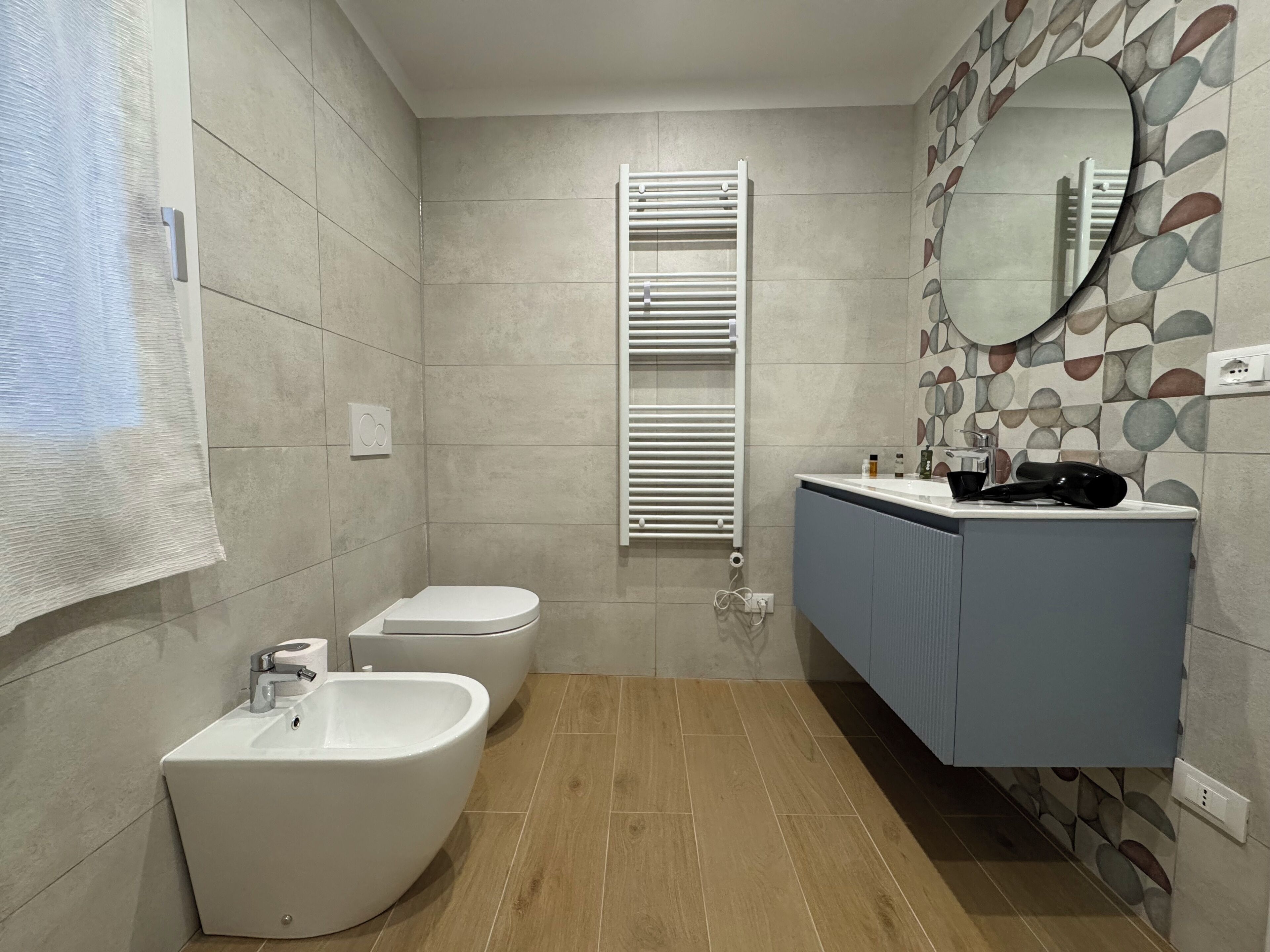 Un baño moderno con bidé, inodoro y lavabo con espejo.