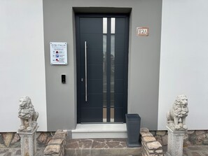 A modern building entrance with a black door, a sign for OTB Italia, and two lion statues. - OTB ITALIA - Airport Rooms (Treviso)