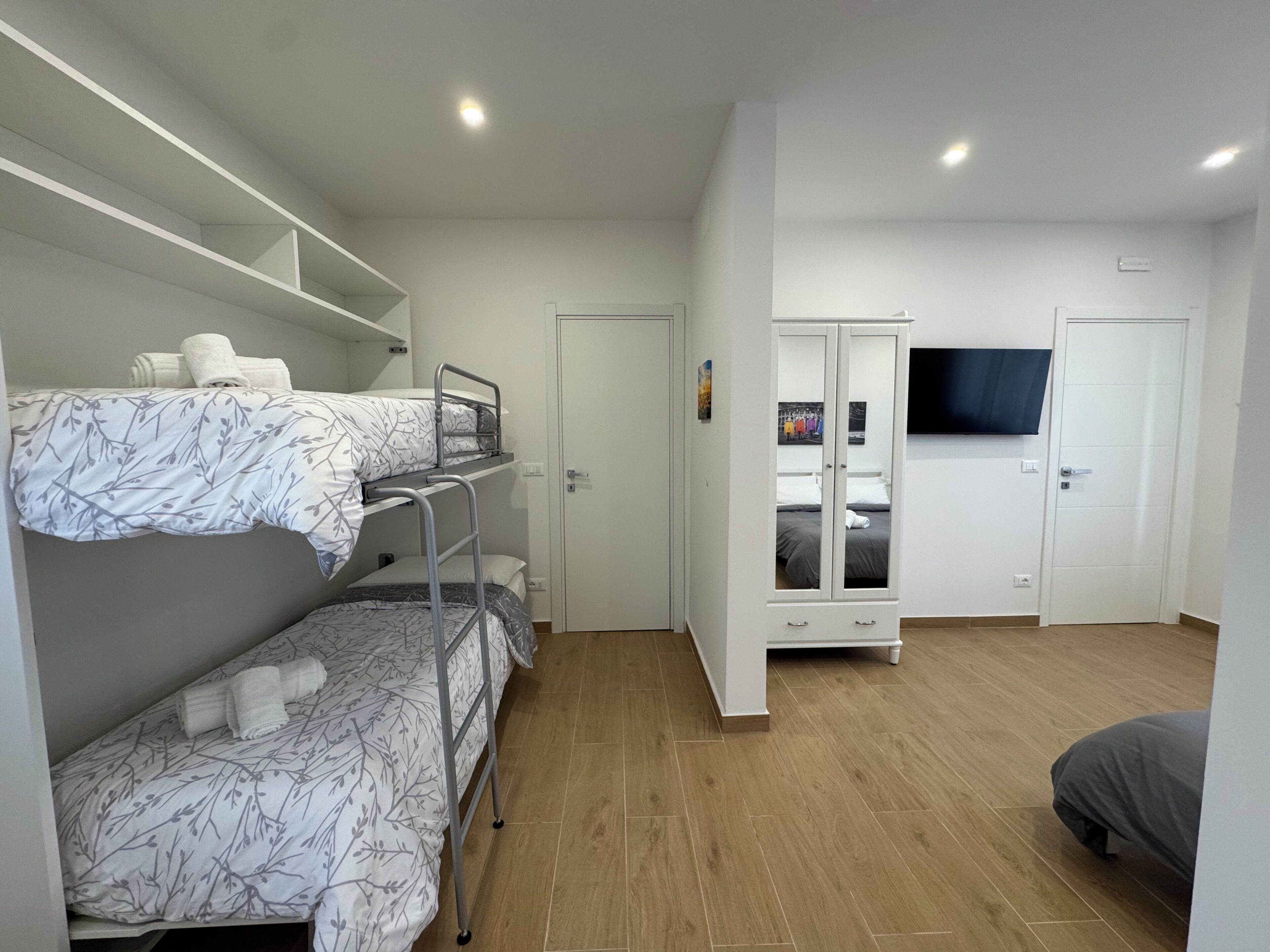 Een kamer met stapelbedden, een kledingkast, een televisie en een deur.