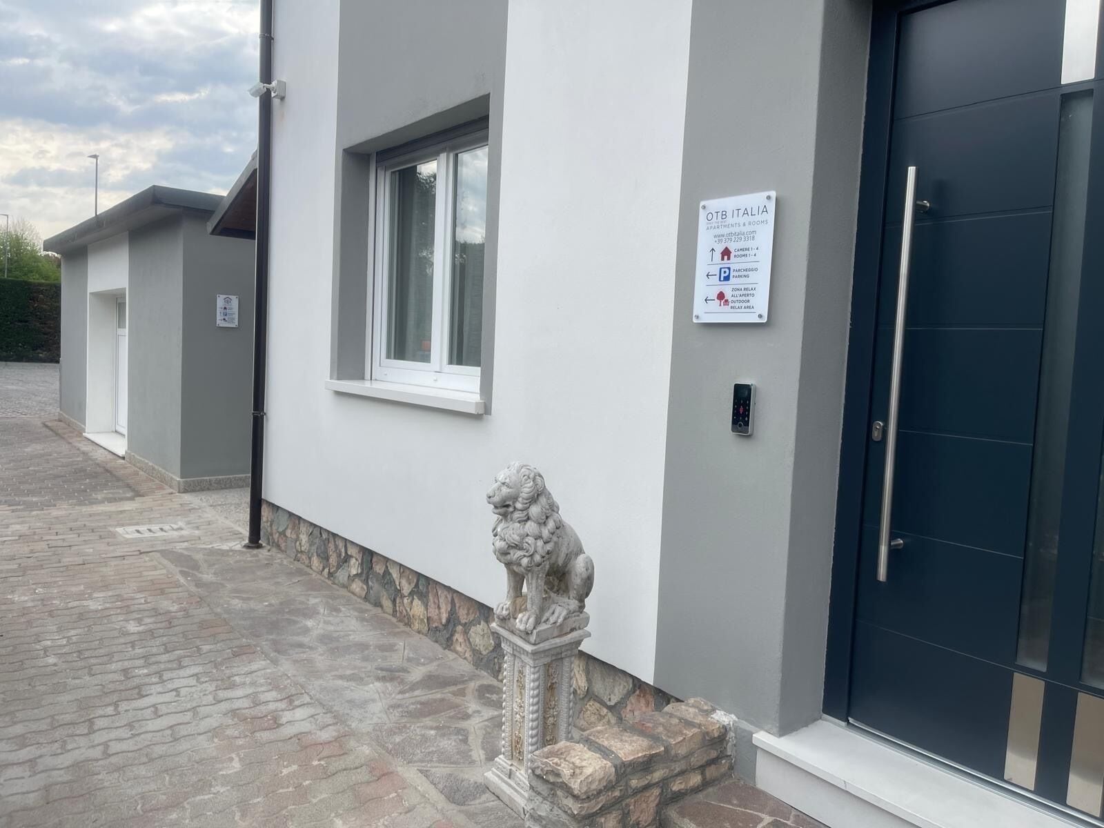 A building exterior with a stone lion statue, a black door, and a sign indicating parking and relaxation areas.
