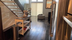 A modern kitchen with a wooden staircase, a kitchen island, and a large window. - Modern Living with Rooftop Views (Pittsburgh)