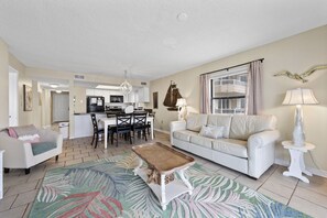 A living room with a sofa, coffee table, and a dining area with chairs and a table. - 🌞Beachfront 3BR w/ Community Pool | Gulf Views from Balcony | Sunswept 201🌞 (Orange Beach)