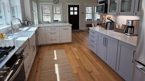 A modern kitchen with a central island, built-in appliances, and large windows. - Pure Blue on M22 in Northport Village (Northport)