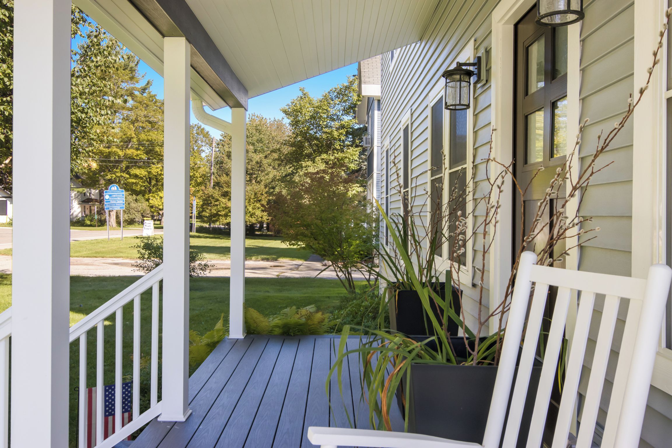 A porch with a white railing, a bench, and a potted plant.