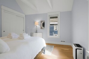 A bedroom with a bed, a lamp, a window, and a radiator.