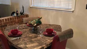 A dining area with a round table set for four, surrounded by red chairs.
