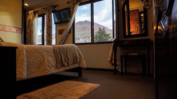 Ein Schlafzimmer mit Bett, Fernseher, Schreibtisch und Blick auf einen Berg.