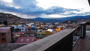 Un paysage urbain caractérisé par une diversité de styles architecturaux et dominé, à l’arrière-plan, par une chaîne de montagnes imposante.