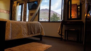 Ein Schlafzimmer mit Bett, Fernseher, Fenster mit Bergblick, Kamin und einer Tür mit einer Nummer.