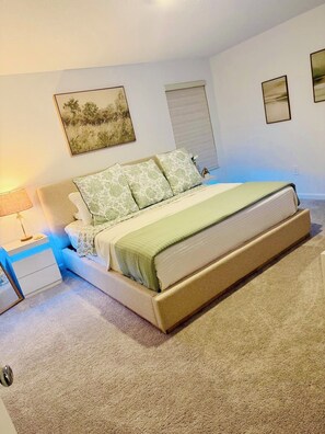 Ein Schlafzimmer mit einem Bett, einem Nachttisch, einer Lampe und gerahmten Bildern an der Wand.