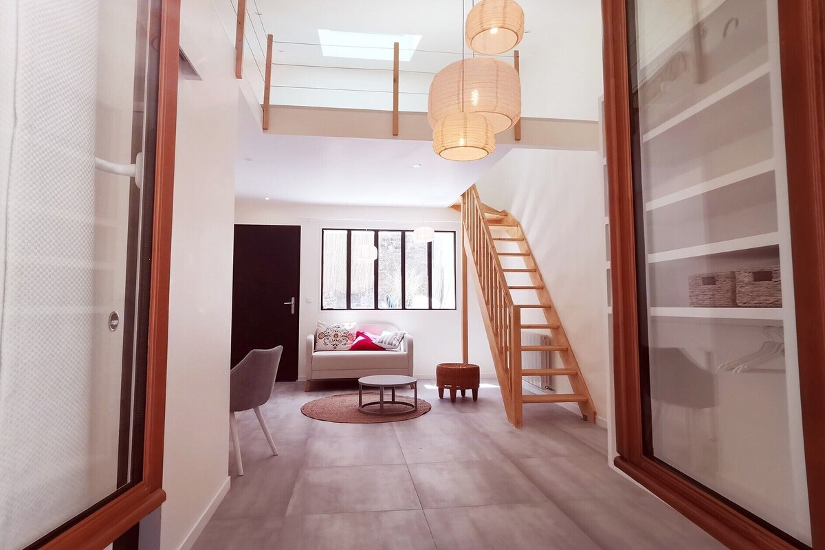 A modern interior with a staircase, a sofa, a coffee table, and a hanging light fixture.