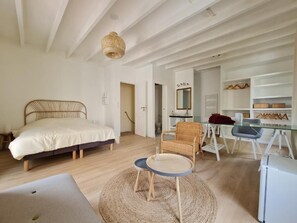 A bedroom with a bed, a chair, a small table, a desk, and a refrigerator. - Le Saint Christophe (Aubervilliers)