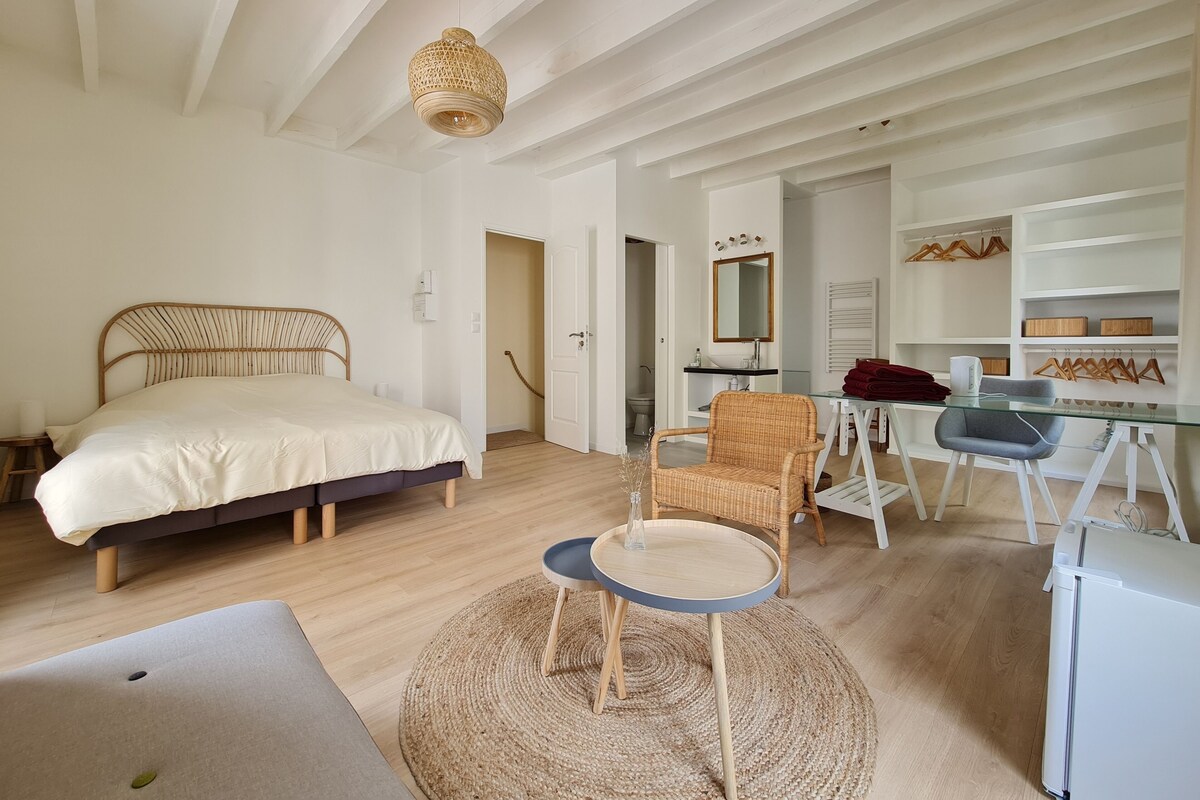 A bedroom with a bed, a desk, a chair, a mirror, and a wardrobe.