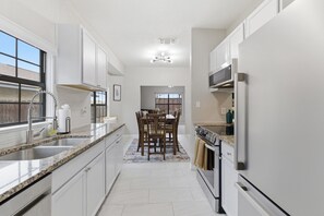 Eine moderne Küche mit weißen Schränken, einer Granit-Arbeitsplatte und einem eingebauten Backofen.