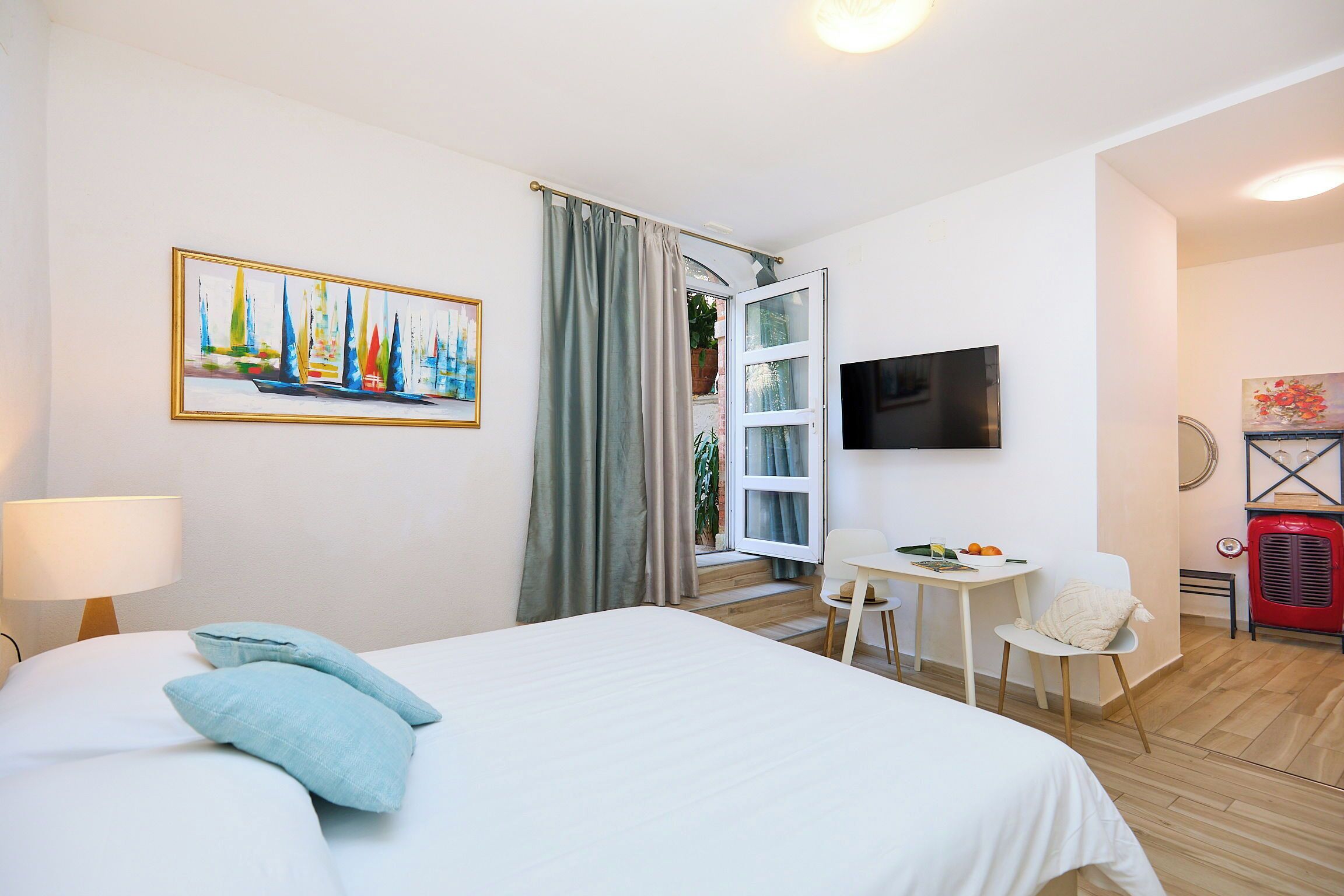 Een hotelkamer met een bed, een bureau met stoel, een televisie en een schilderij aan de muur.