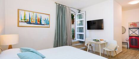 Een hotelkamer met een bed, een bureau met stoel, een televisie en een schilderij aan de muur.