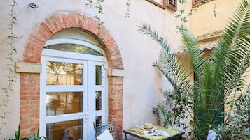 A courtyard with a white door, a small table with chairs, and potted plants.