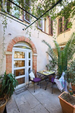 A courtyard with a white door, a small table with chairs, and potted plants. - Studio Chloe - Heart of Old Town (Dubrovnik)