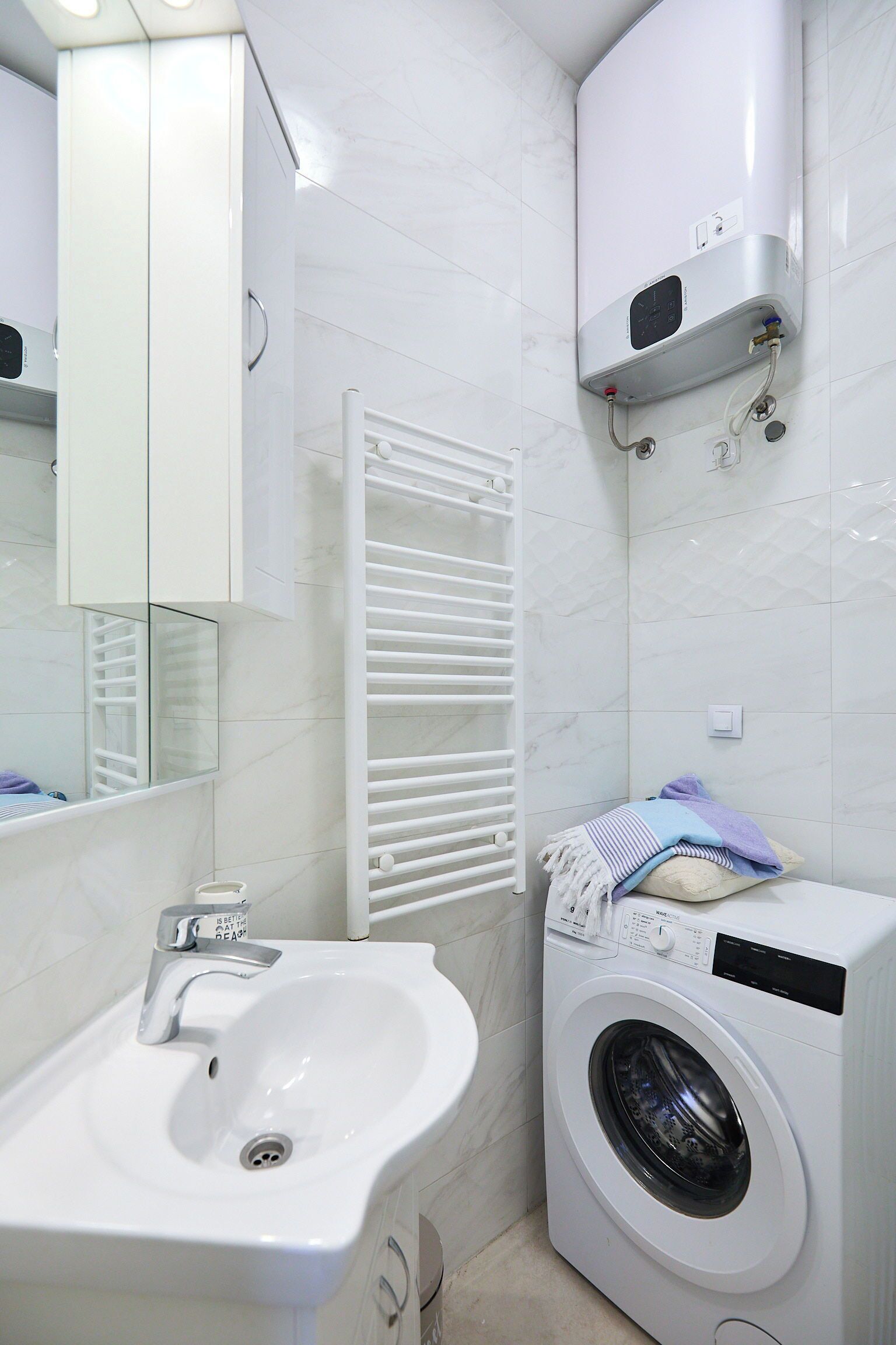 Une salle de bain équipée d’un lavabo, d’un miroir, d’un porte-serviettes et d’un lave-linge.