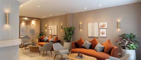 A modern living room with a sofa, armchairs, a coffee table, and decorative plants.
