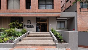 A building with a brick facade, a sign reading 'boma house,' and a set of concrete steps leading to the entrance. - Bomma House - Parque 93 (Bogotá)