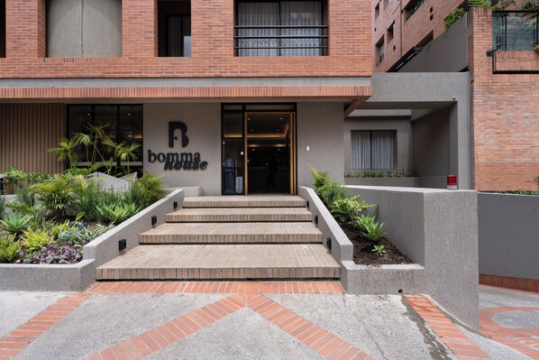 Un edificio de fachada de ladrillo, un letrero que dice 'boma house' y un conjunto de escalones de concreto que conducen a la entrada.