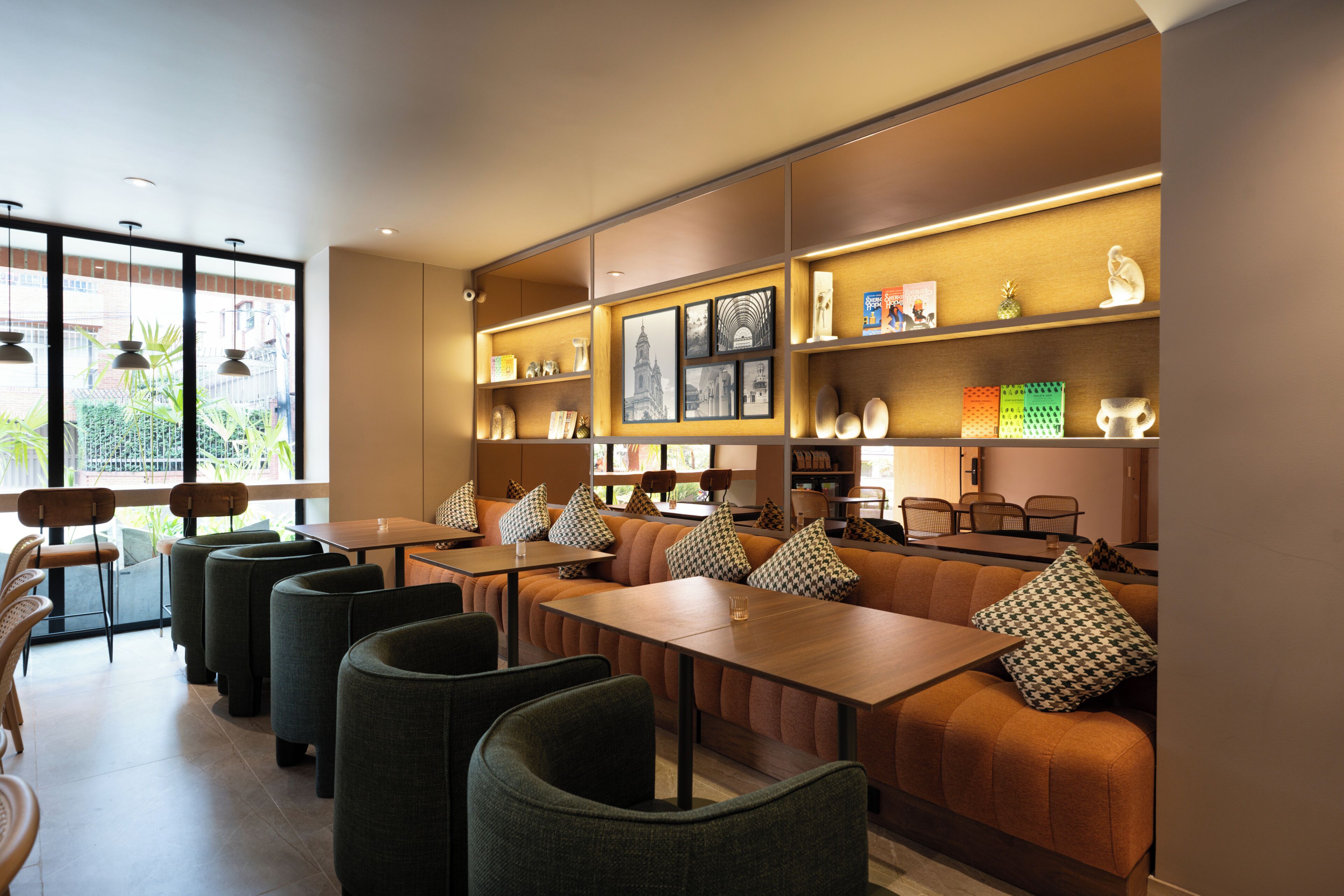 Un restaurant moderne avec des tables hautes, des sièges confortables et une vue sur la verdure environnante.