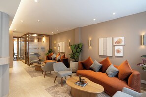 Un salon moderne avec un canapé, des fauteuils, une table basse et une plante en pot.