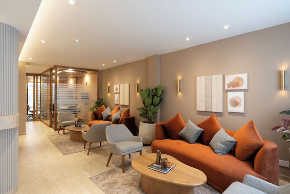 Una sala de estar moderna con un sofá, sillones, una mesa de centro y una planta en maceta.