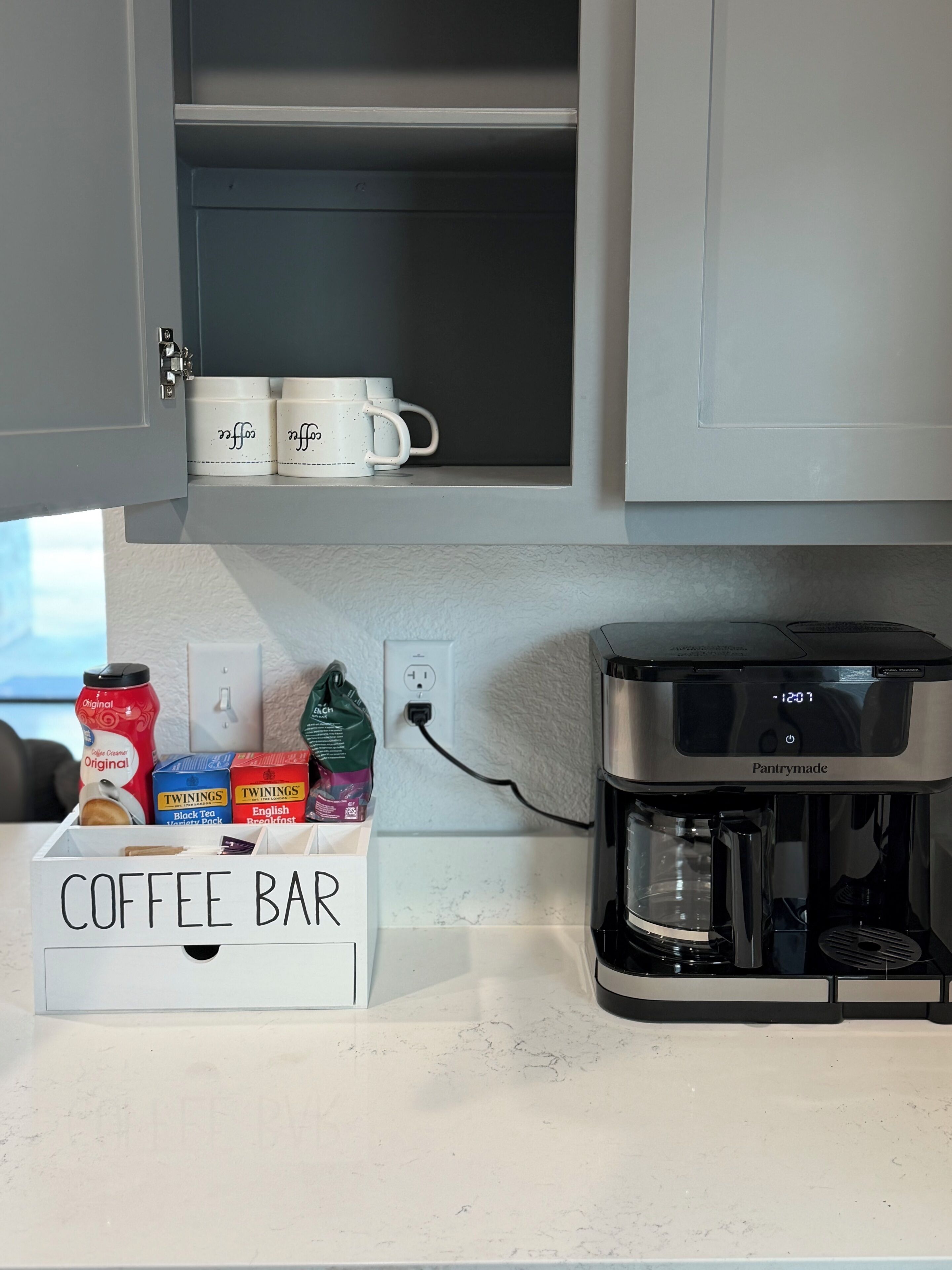 A kitchen with a coffee bar setup including a coffee maker, mugs, and coffee containers.