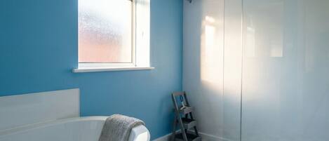 Un baño con una bañera blanca, una ventana, ducha y piso a cuadros.