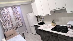 A compact kitchen with a dining area, white cabinets, a built-in stove, and a refrigerator.