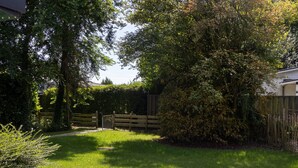 A well-maintained garden with a paved pathway, a wooden fence, and lush greenery. - House & More Near the Ijsselmeer (Lemmer)