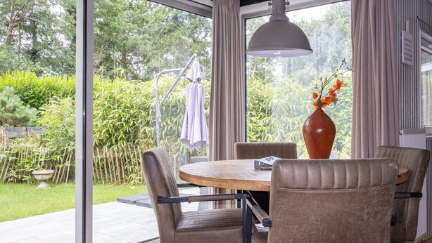 A dining area with a round table, chairs, a vase with flowers, and a hanging light fixture. - House & More Near the Ijsselmeer (Lemmer)