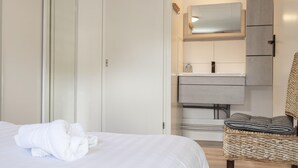 A bedroom with a bed, a chair, a wardrobe, and a bathroom with a mirror and cabinets. - House & More Near the Ijsselmeer (Lemmer)