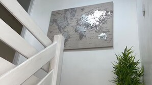 Eine Treppe mit weißen Geländern, ein Wandbild mit einer Weltkarte und ein Blumentopf.