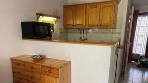 Eine Küche mit Holzausstattung, einer Mikrowelle und einer kleinen Holzkommode.