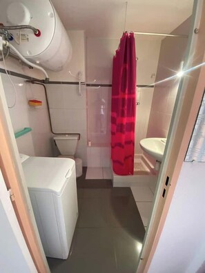 A compact bathroom with a toilet, a sink, and a shower area. - Air-conditioned studio with balcony in St-Raphaël (Saint-Raphaël)