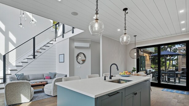 A modern kitchen with a central island, a dining area with a round table, and a staircase leading to an upper level. - Beautiful home located in OBP. Located on a beach block. Great home when visiting the island, all the amenities included. (OCEAN BEACH)