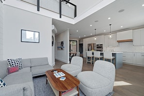 A modern apartment with a living room, dining area, and kitchen.